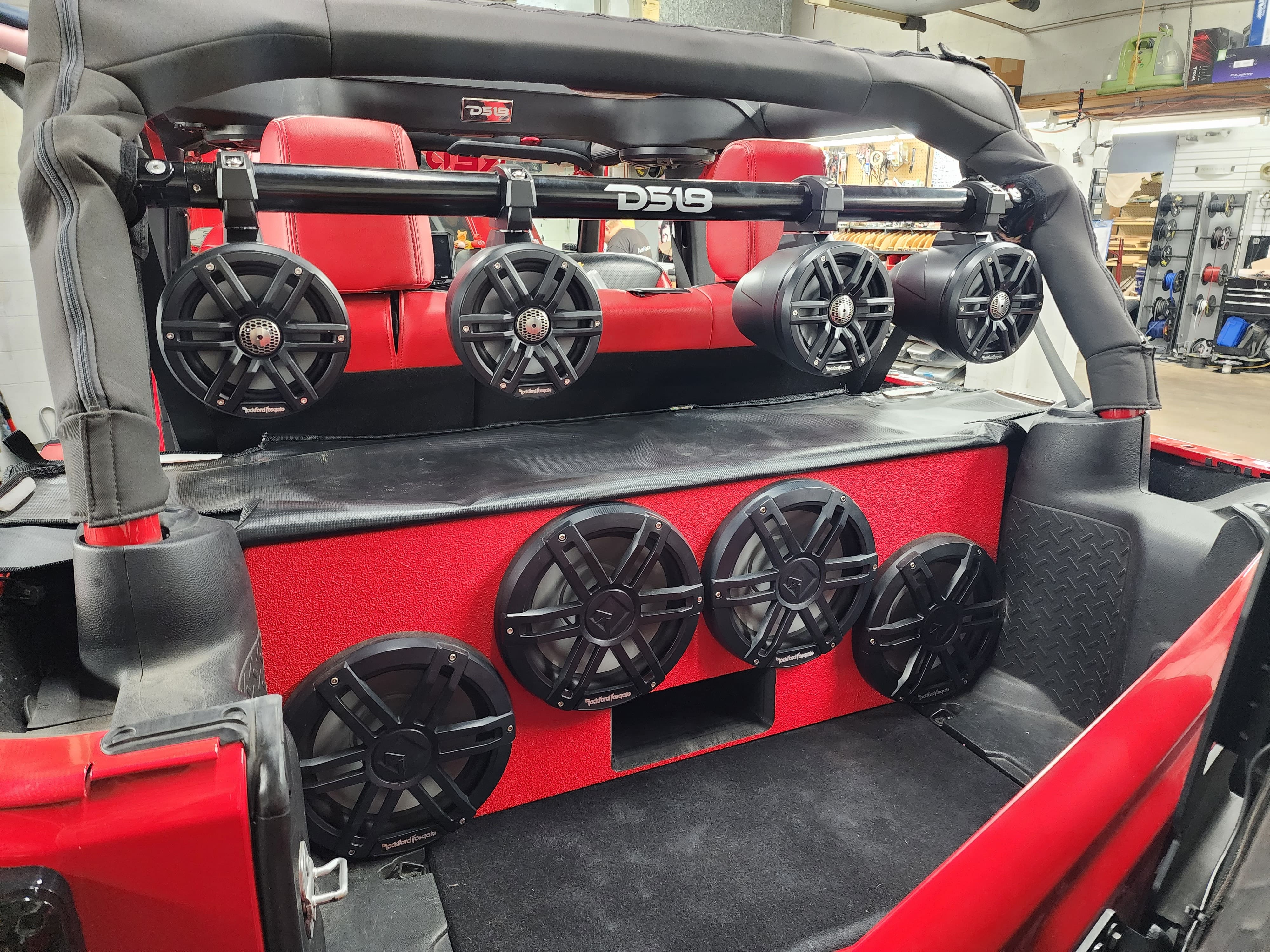 Jeep interior with red seats, roll bar mounted speaker pods and a red rear panel holding six speakers.