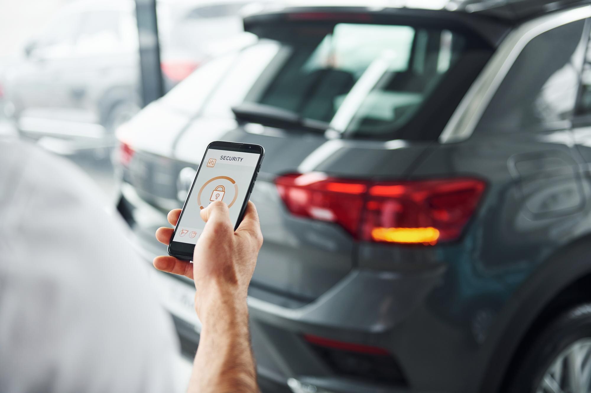 Hand holding a phone showing a car security app with a padlock icon beside a parked SUV.