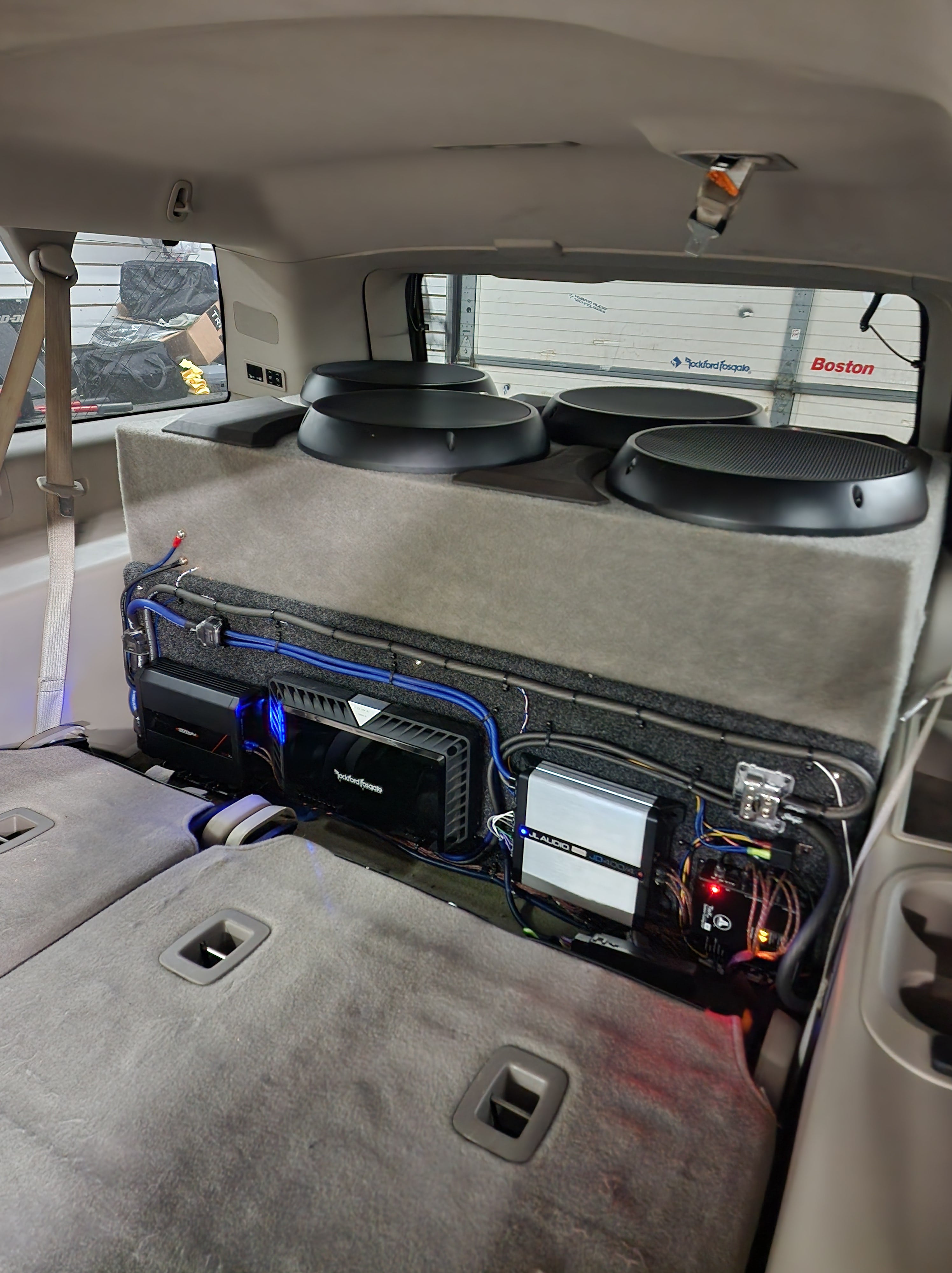 Two subwoofers and a rack of wired amplifiers mounted behind the rear seats of an SUV.