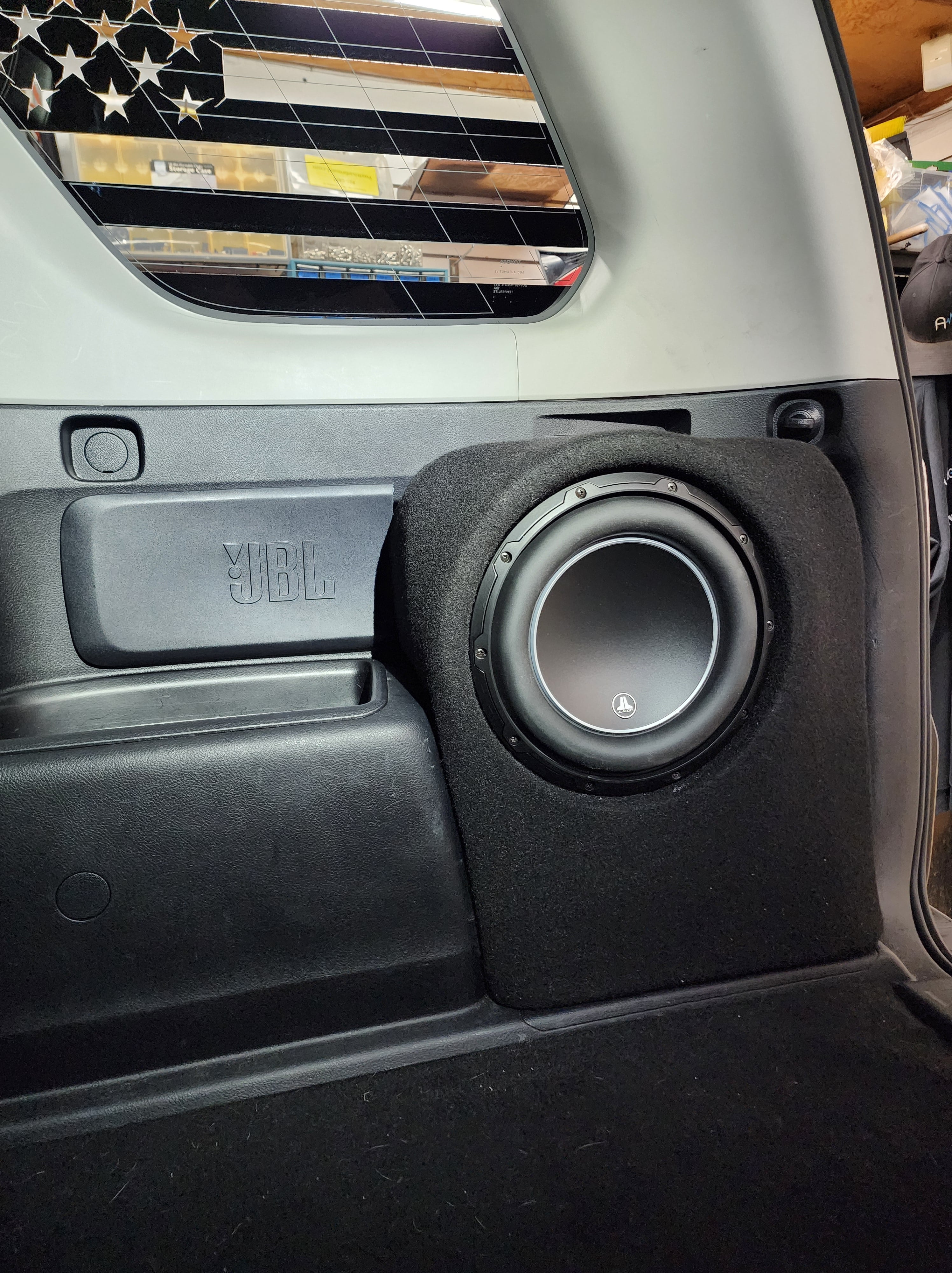 Single subwoofer in a carpeted enclosure built into the rear side panel of a truck cab