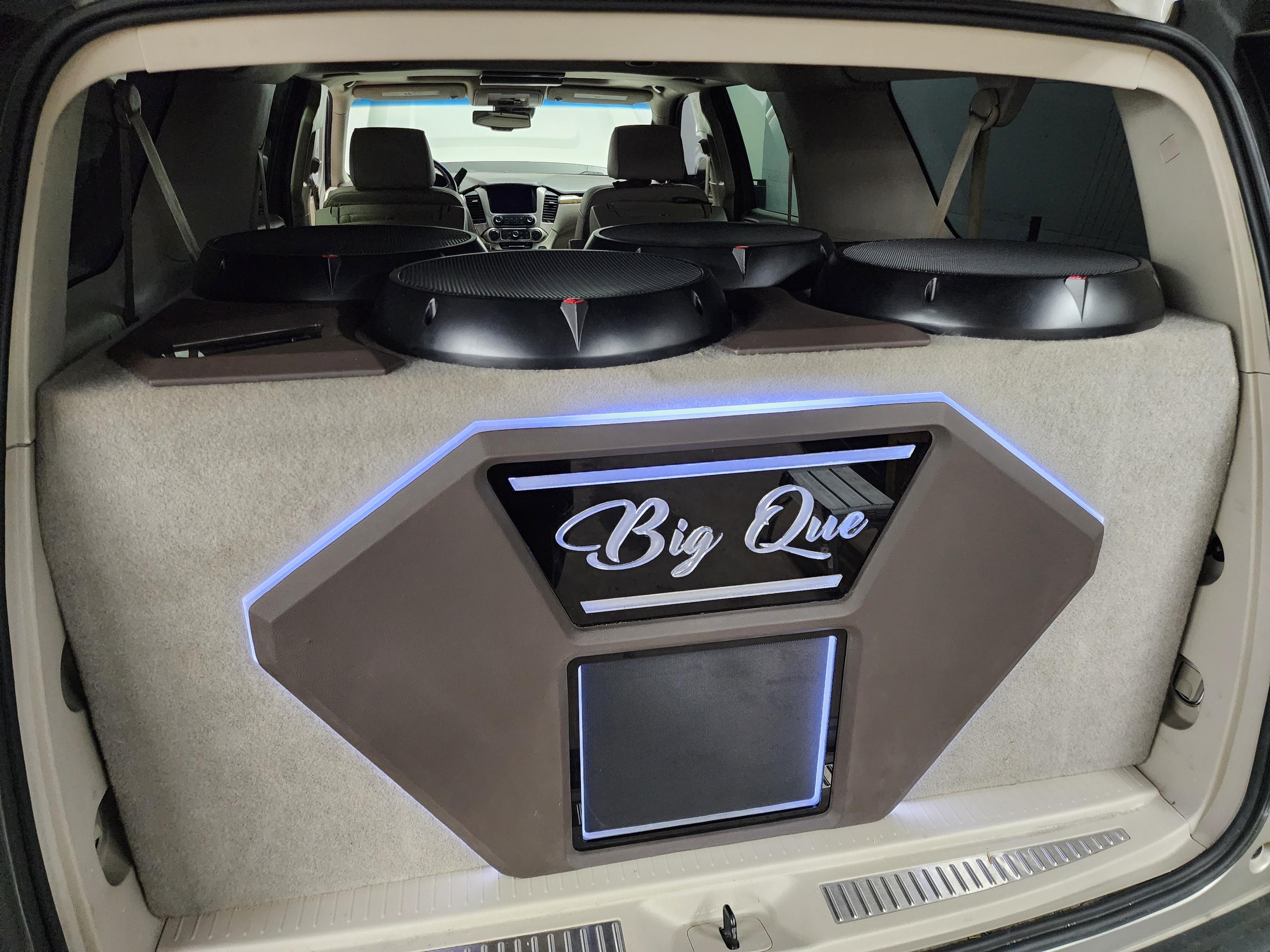 SUV cargo build with four subwoofers across the rear seat back and a lit custom enclosure panel with script lettering